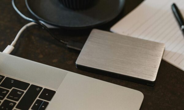 Free Closeup of an external hard drive connected to a laptop with a USB cable on a desk. Stock Photo